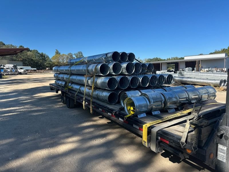 Bundles of galvanized culvert pipe stacked and strapped across a flatbed trailer