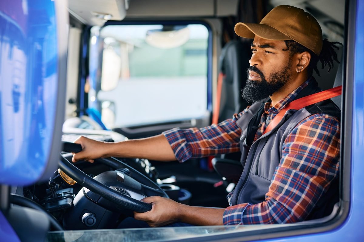 A driver in the cab of a red day cab tractor